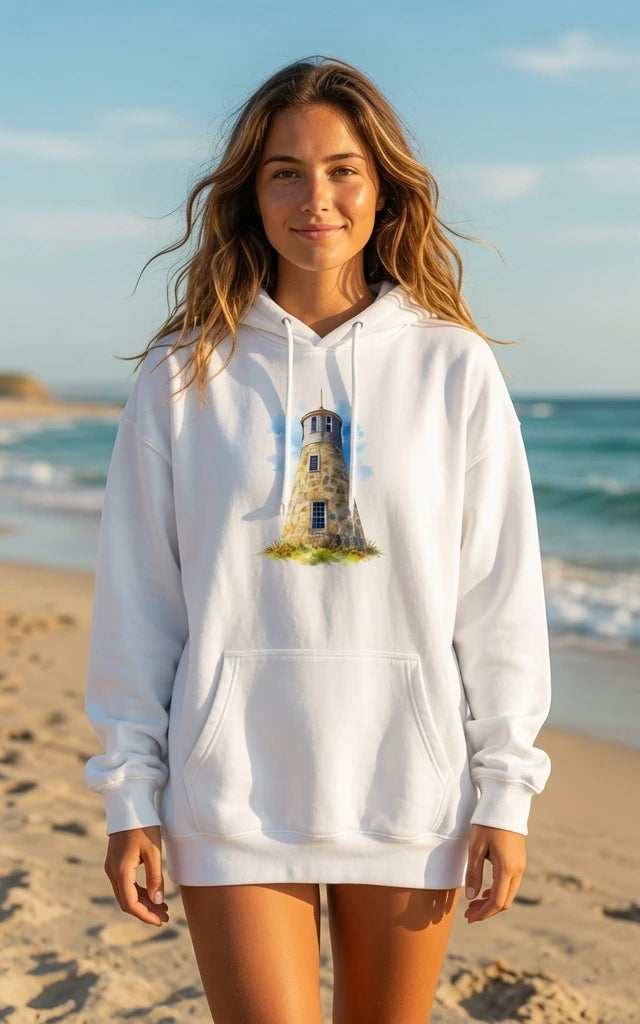 Woman wearing a white Cape Cod Lighthouses – Point Gammon Watercolor Coastal Hoodie with a lighthouse design on a beach