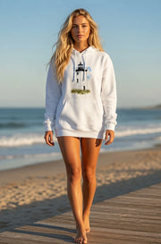 Woman wearing a white Cape Cod Lighthouses – Long Point Watercolor Coastal Hoodie with a lighthouse design on a beach